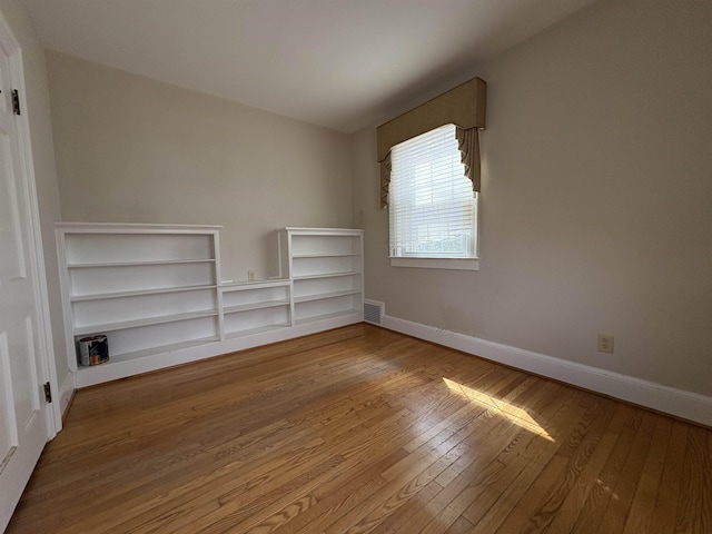 spare room featuring visible vents, baseboards, and hardwood / wood-style floors