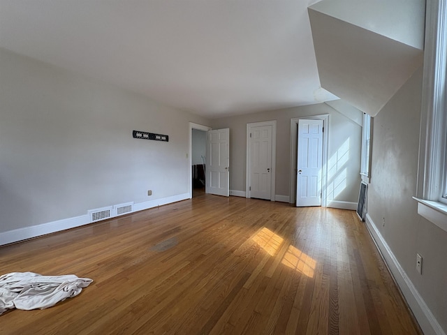 interior space featuring baseboards, visible vents, and hardwood / wood-style floors