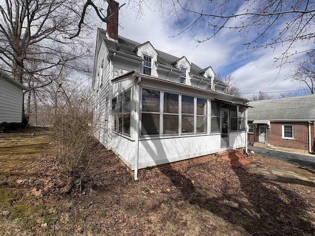 view of side of home with a sunroom and a chimney