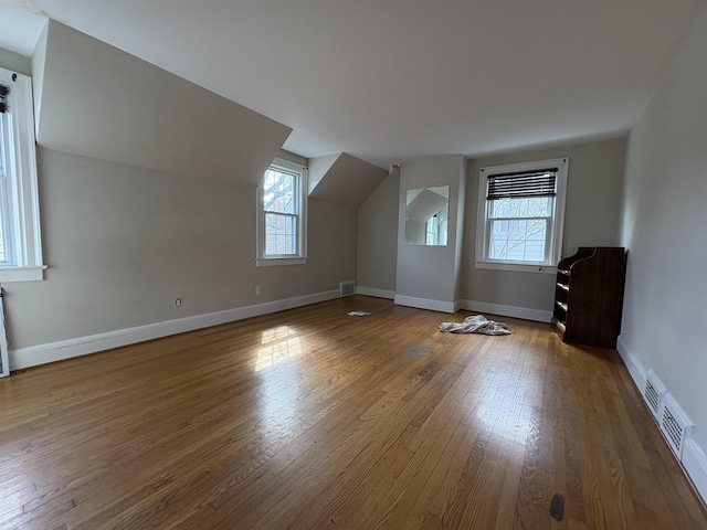 bonus room with lofted ceiling, visible vents, baseboards, and hardwood / wood-style flooring