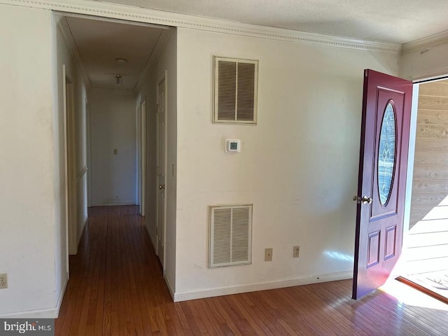 foyer entrance with wood-type flooring, visible vents, and crown molding