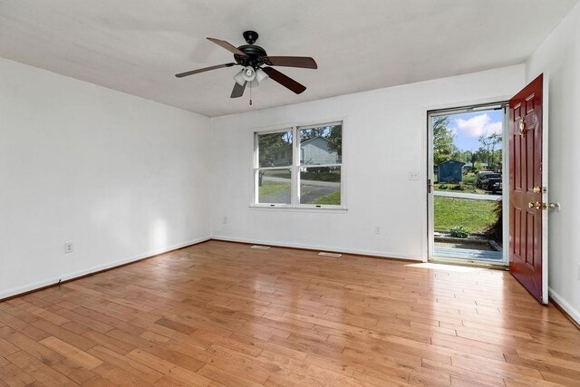 spare room with baseboards, light wood finished floors, ceiling fan, and visible vents