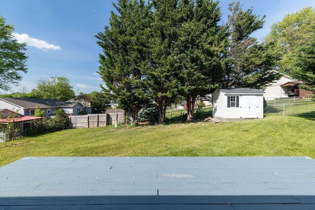 view of yard with an outdoor structure, a deck, a shed, and a fenced backyard