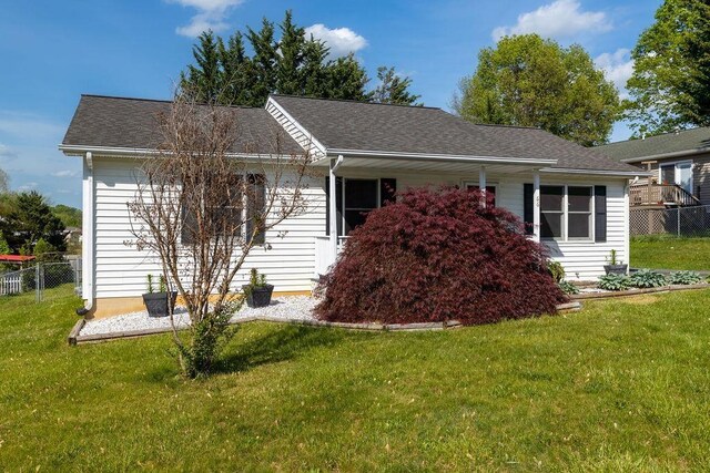 view of front of house with fence, a shingled roof, and a front yard