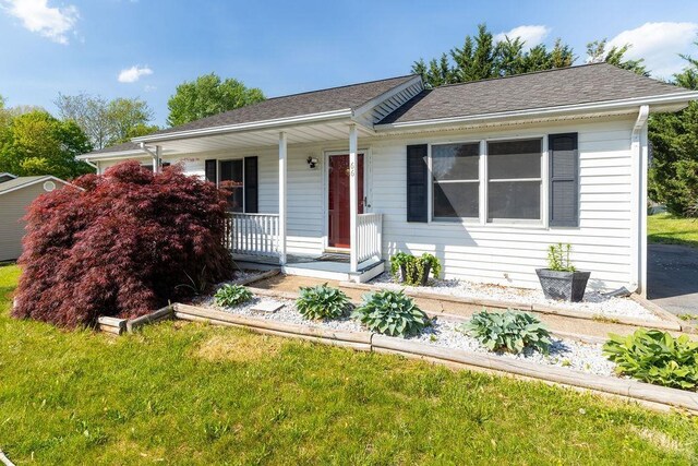 view of front of house featuring a porch, roof with shingles, and a front lawn