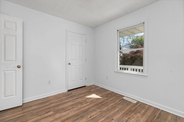 unfurnished bedroom with baseboards, dark wood-style flooring, and visible vents