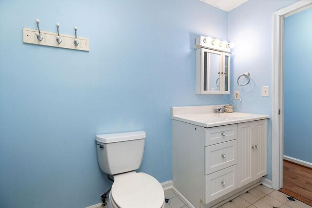 bathroom with baseboards, vanity, and toilet