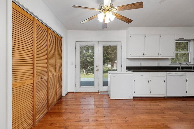 kitchen with white cabinets, dark countertops, light wood-style flooring, and dishwasher