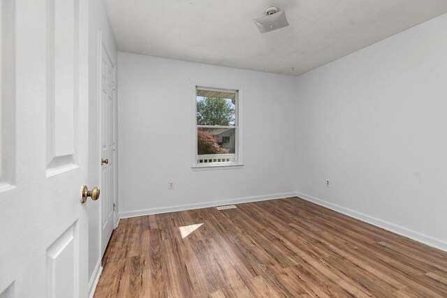 unfurnished room featuring visible vents, baseboards, and wood finished floors