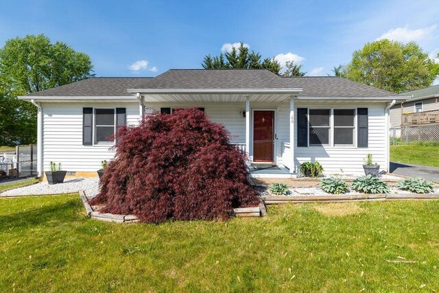 view of front of home with fence, a shingled roof, and a front yard