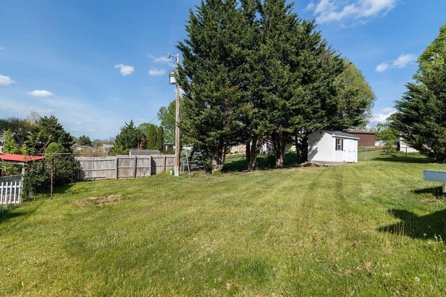 view of yard with fence, an outbuilding, and a shed
