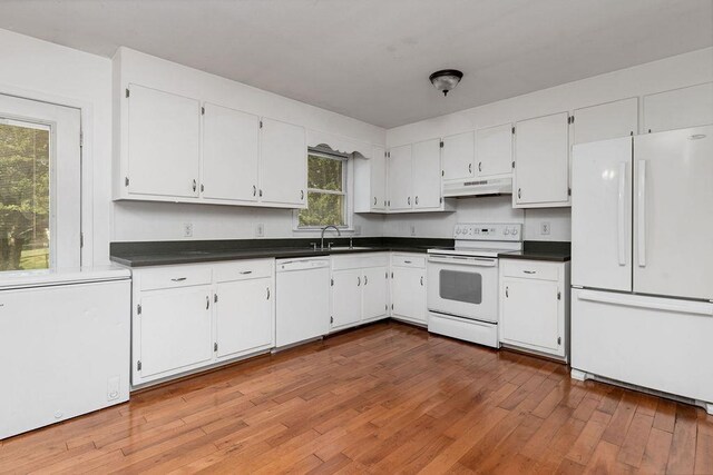 kitchen featuring wood finished floors, dark countertops, white appliances, white cabinetry, and under cabinet range hood