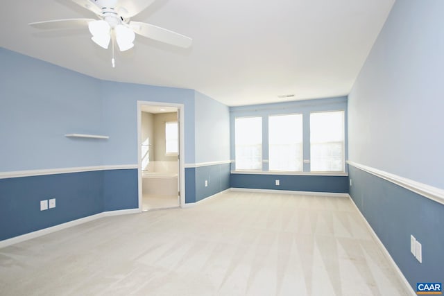 carpeted spare room featuring visible vents, baseboards, and ceiling fan