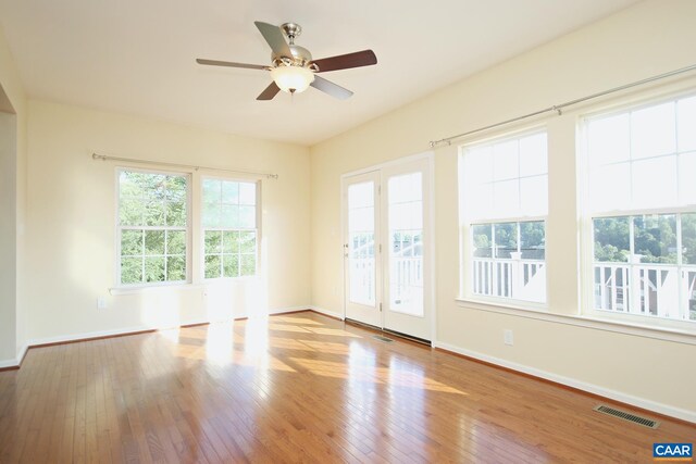 empty room with hardwood / wood-style floors, visible vents, baseboards, and ceiling fan