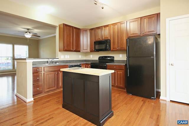kitchen featuring brown cabinets, light wood-type flooring, black appliances, a peninsula, and ceiling fan