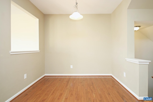 unfurnished dining area featuring light wood-type flooring and baseboards