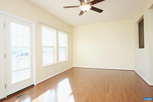 unfurnished room with baseboards, wood finished floors, visible vents, and a ceiling fan
