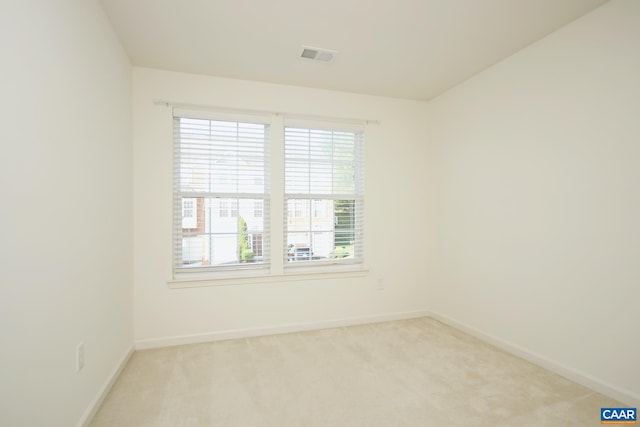 spare room featuring baseboards, visible vents, and light colored carpet