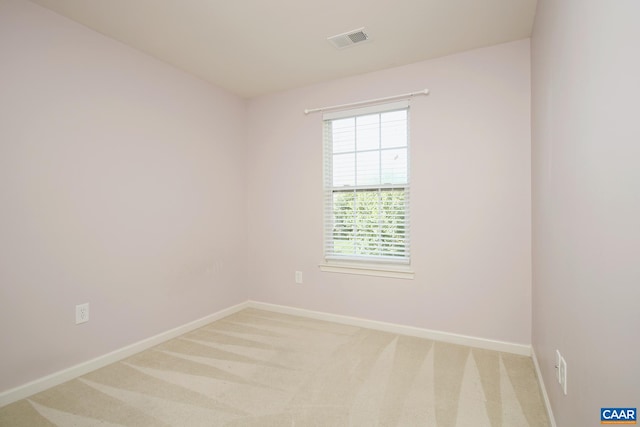 unfurnished room featuring baseboards, visible vents, and light carpet