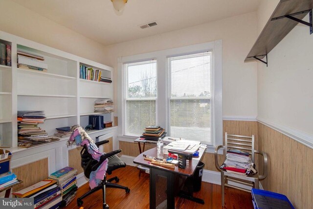 office area with hardwood / wood-style flooring and wood walls