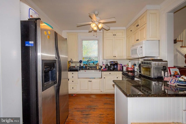 kitchen featuring stainless steel refrigerator with ice dispenser, dark wood-type flooring, sink, ceiling fan, and dark stone counters