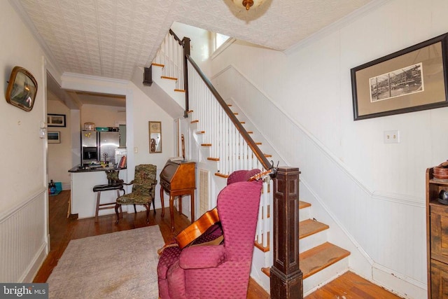 stairway with hardwood / wood-style flooring and ornamental molding