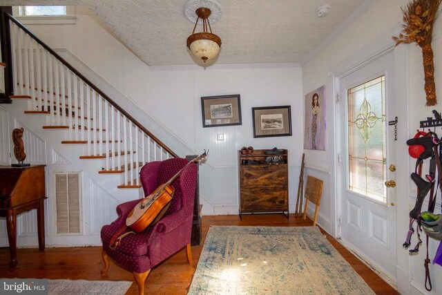 foyer with ornamental molding and hardwood / wood-style floors