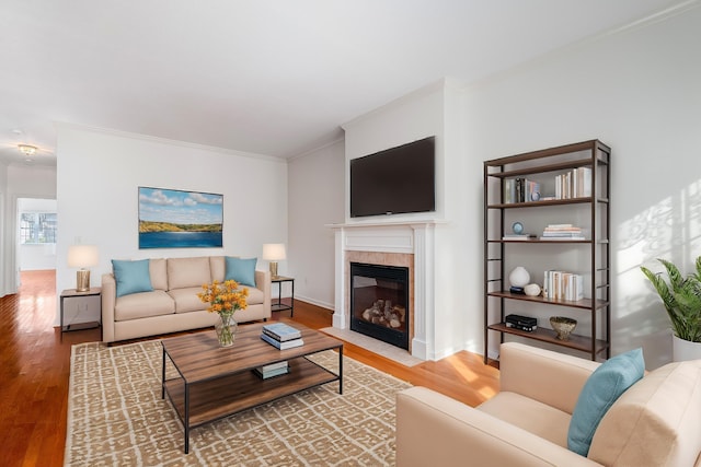 living room featuring a tiled fireplace, hardwood / wood-style flooring, and ornamental molding