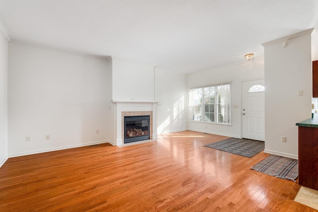 unfurnished living room featuring crown molding, a fireplace, and light hardwood / wood-style floors