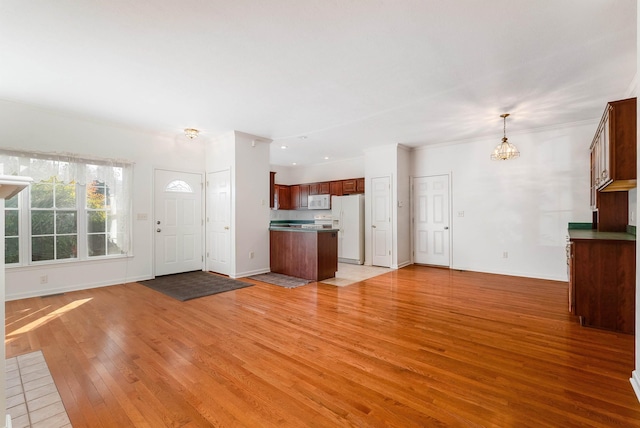 unfurnished living room featuring ornamental molding, a notable chandelier, and light hardwood / wood-style floors