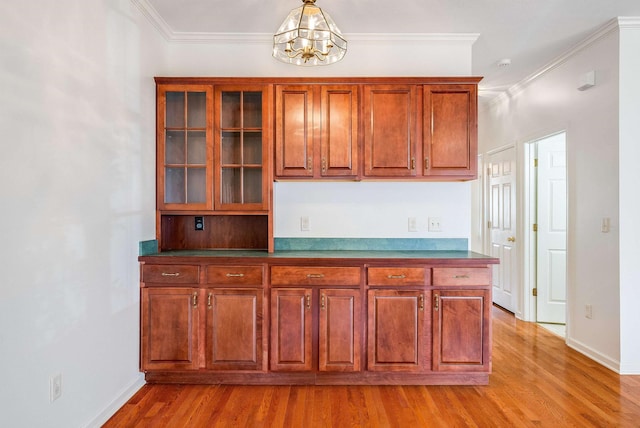 kitchen featuring an inviting chandelier, crown molding, light hardwood / wood-style flooring, and decorative light fixtures