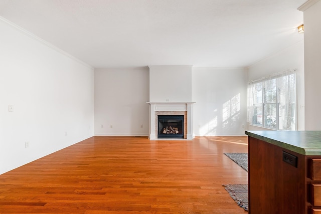 unfurnished living room featuring ornamental molding, a tile fireplace, and light wood-type flooring