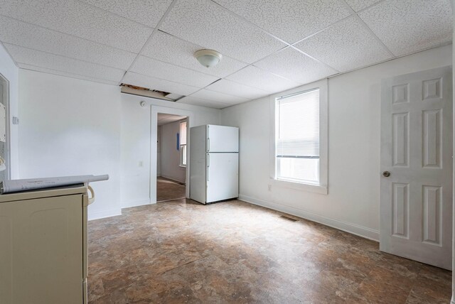 unfurnished bedroom with white refrigerator and a drop ceiling