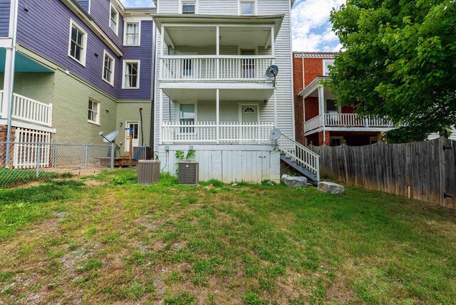 rear view of property featuring central AC and a lawn