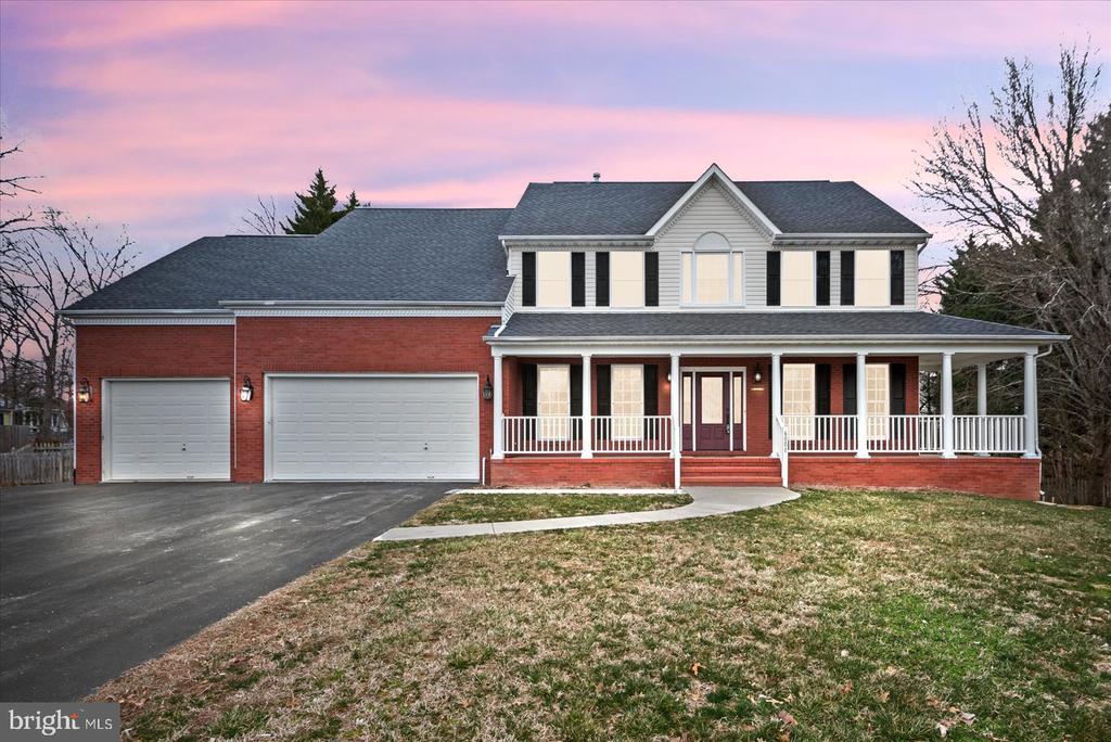 view of front of property with a garage, driveway, a yard, a porch, and brick siding