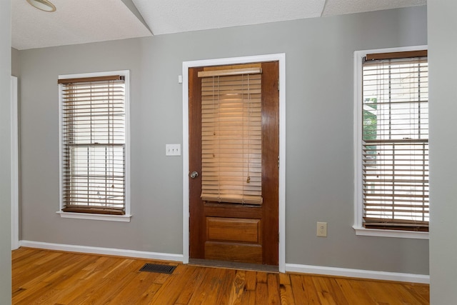 entrance foyer with baseboards, visible vents, and wood finished floors
