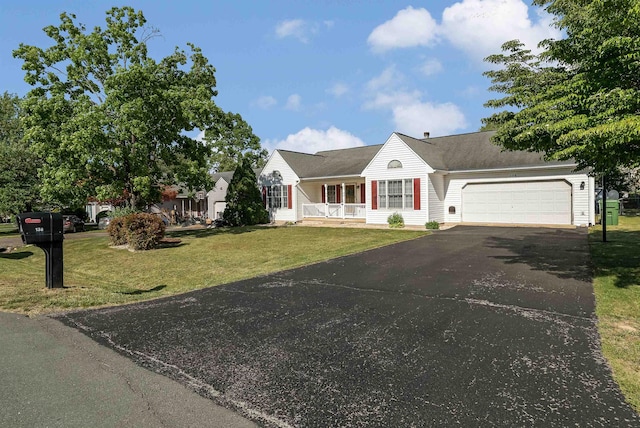 view of front of home featuring a porch, an attached garage, driveway, and a front yard