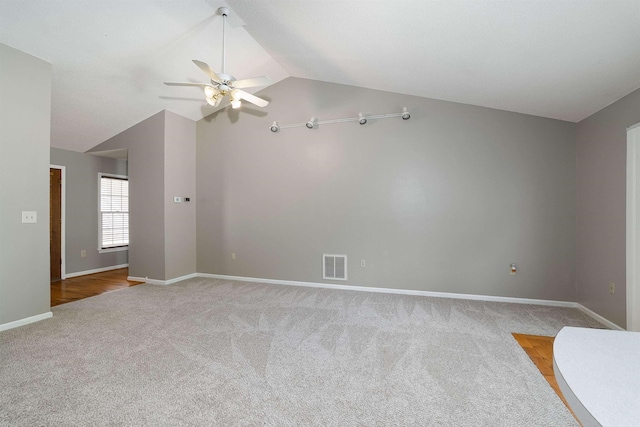 carpeted empty room featuring baseboards, a ceiling fan, vaulted ceiling, and visible vents