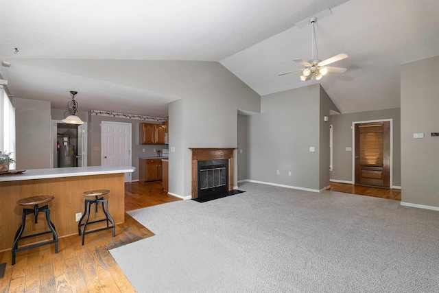 unfurnished living room featuring ceiling fan, a fireplace, light wood-type flooring, baseboards, and lofted ceiling