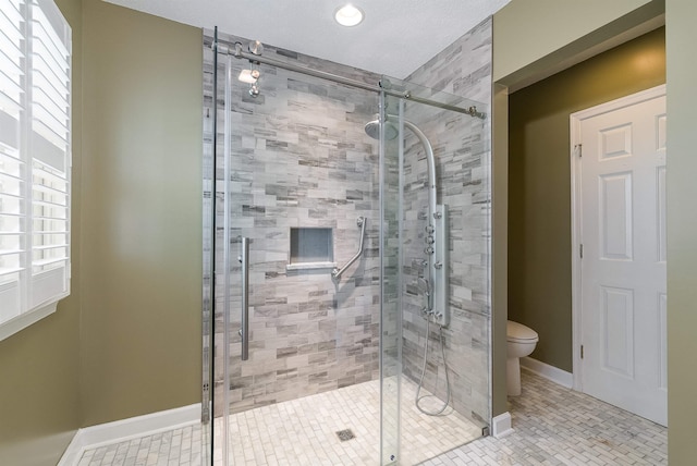 bathroom featuring tile patterned floors, baseboards, a stall shower, and toilet