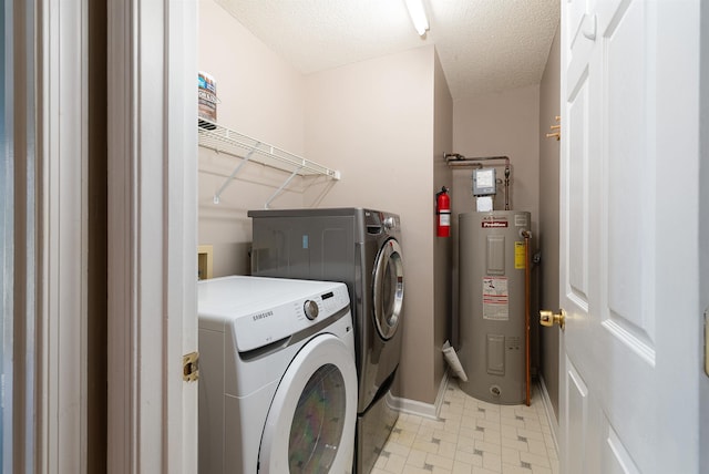 washroom with laundry area, baseboards, water heater, light floors, and washer and dryer
