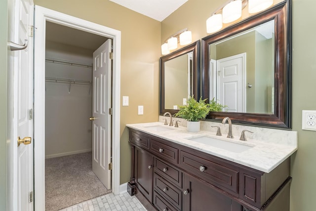 full bath featuring double vanity, a sink, baseboards, and a spacious closet