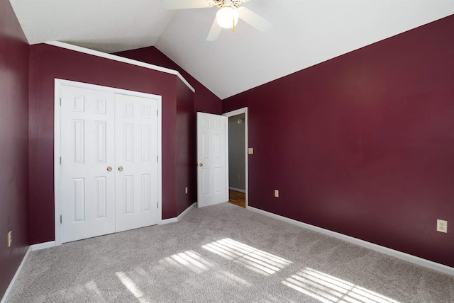 unfurnished bedroom featuring carpet flooring, ceiling fan, baseboards, lofted ceiling, and a closet