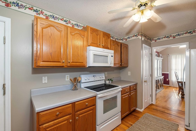 kitchen featuring light wood-type flooring, a ceiling fan, white appliances, and light countertops