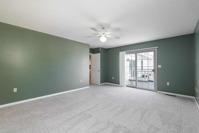 carpeted spare room with baseboards, ceiling fan, a textured ceiling, and visible vents