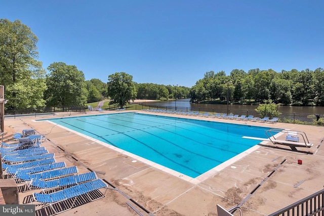 community pool featuring a patio, fence, and a water view