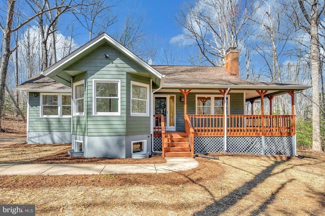 view of front of home with a porch, a chimney, and a shingled roof