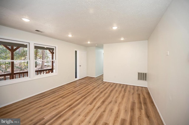 spare room featuring light wood-type flooring, visible vents, and baseboards