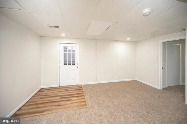 below grade area featuring a drop ceiling, visible vents, baseboards, and carpet