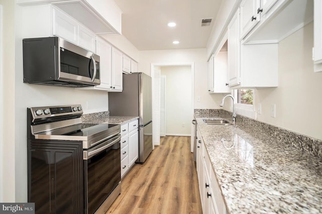 kitchen with visible vents, light wood-type flooring, a sink, white cabinetry, and appliances with stainless steel finishes